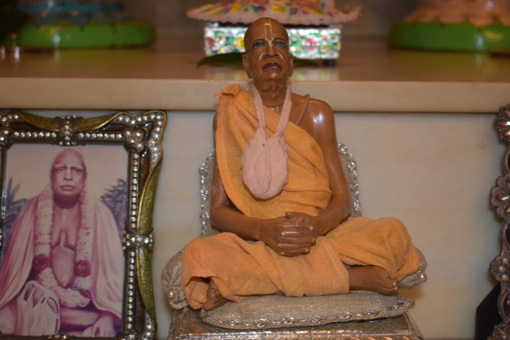 Small Srila Prabhupada on the altar next to a photo of Bhaktivinoda Thakur.