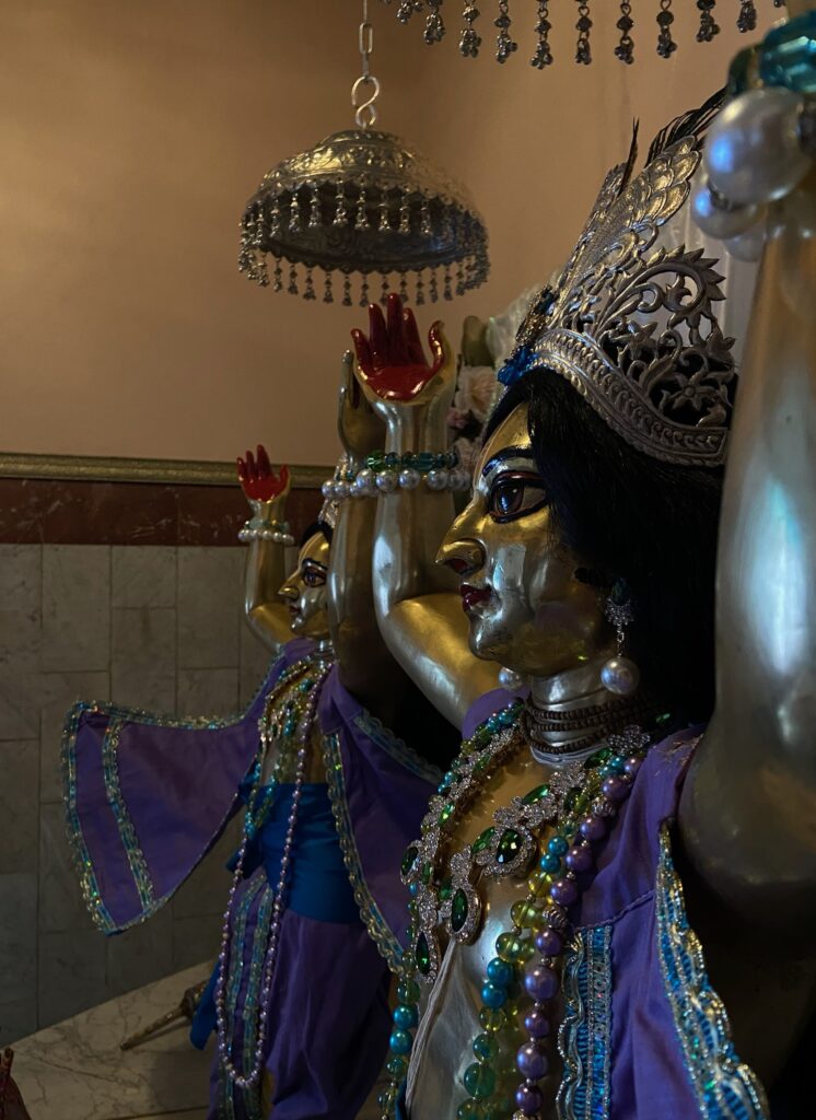 Close of side photo of Deities wearing purple and blue garments with blue, yellow, and green jewelry.
