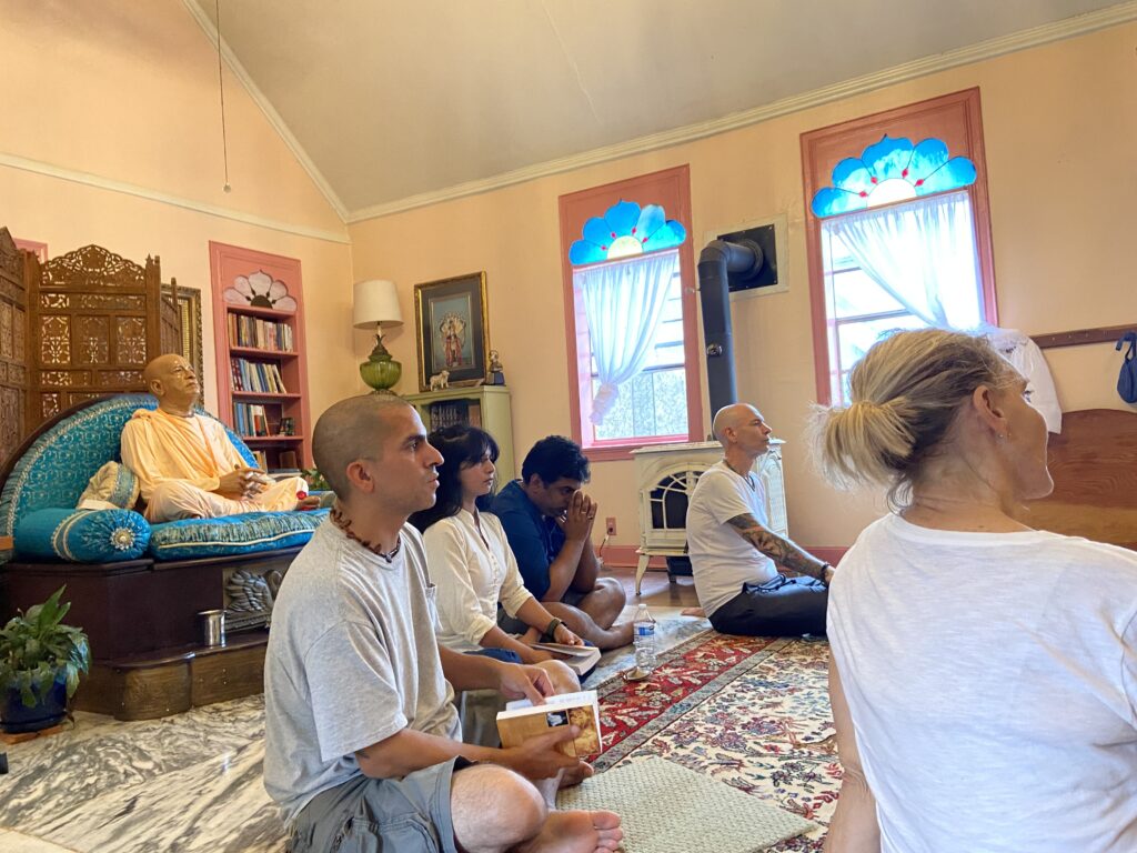 Devotees seated on the floor of the temple room.