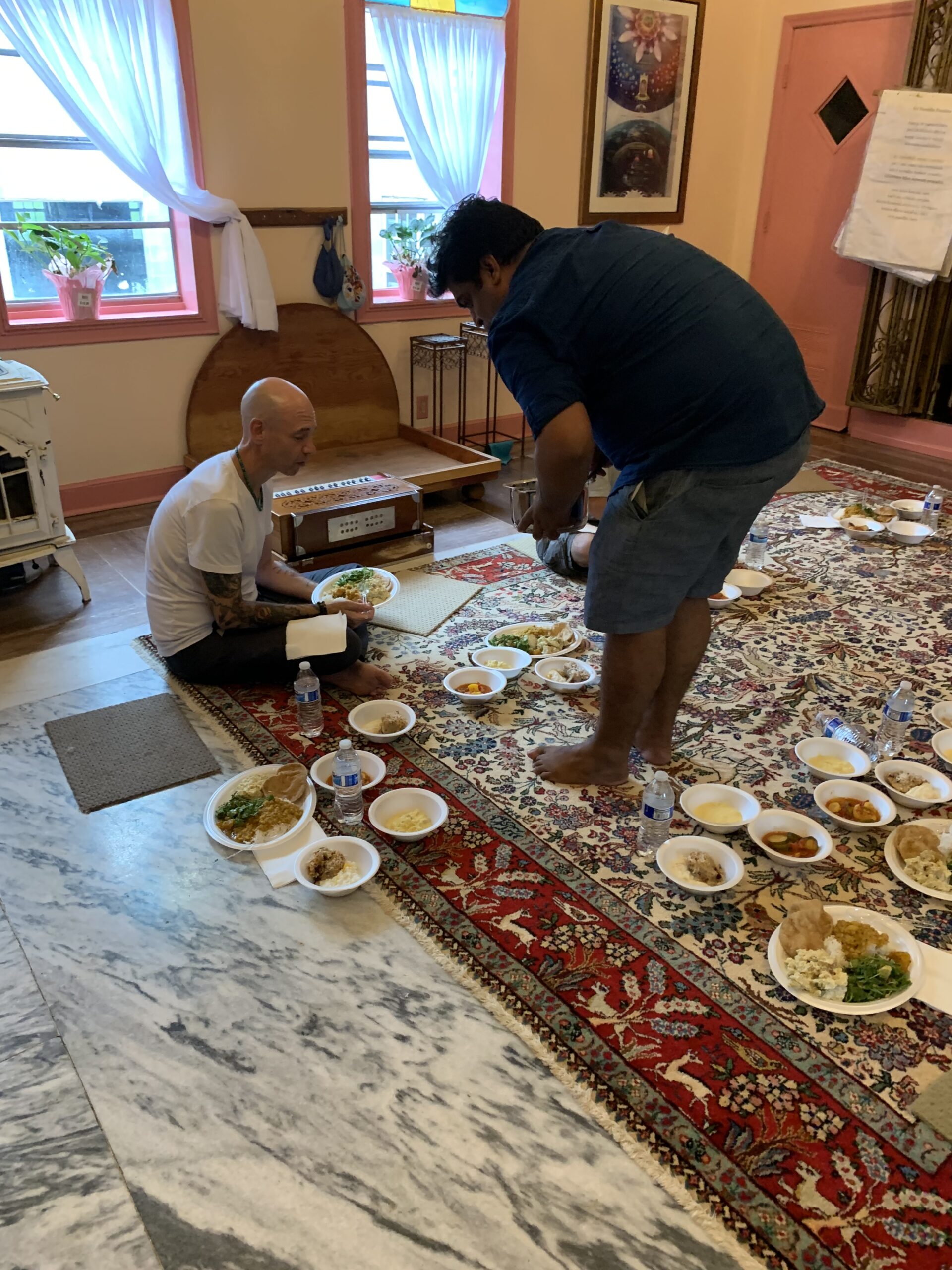 A devotee serving prasadam on the temple room floor.