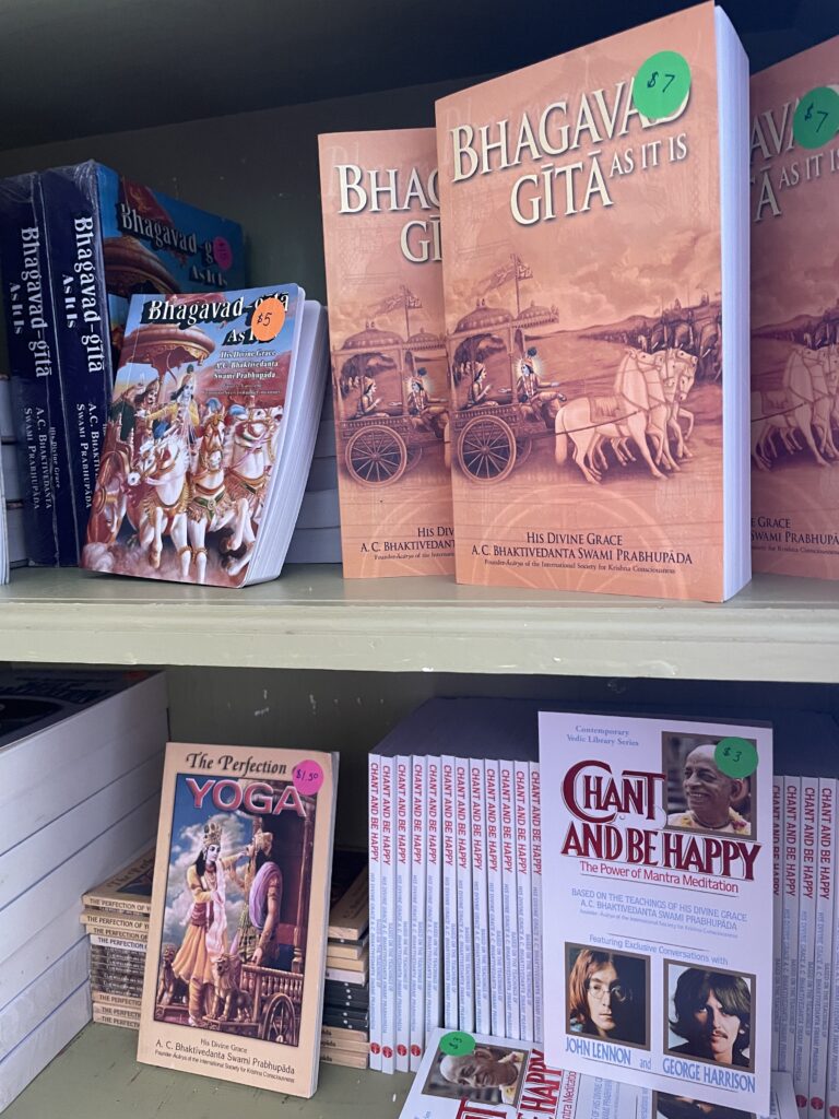 Bookshelf containing copies of Bhagavad Gita, The Perfection of Yoga, and Chant and Be Happy.