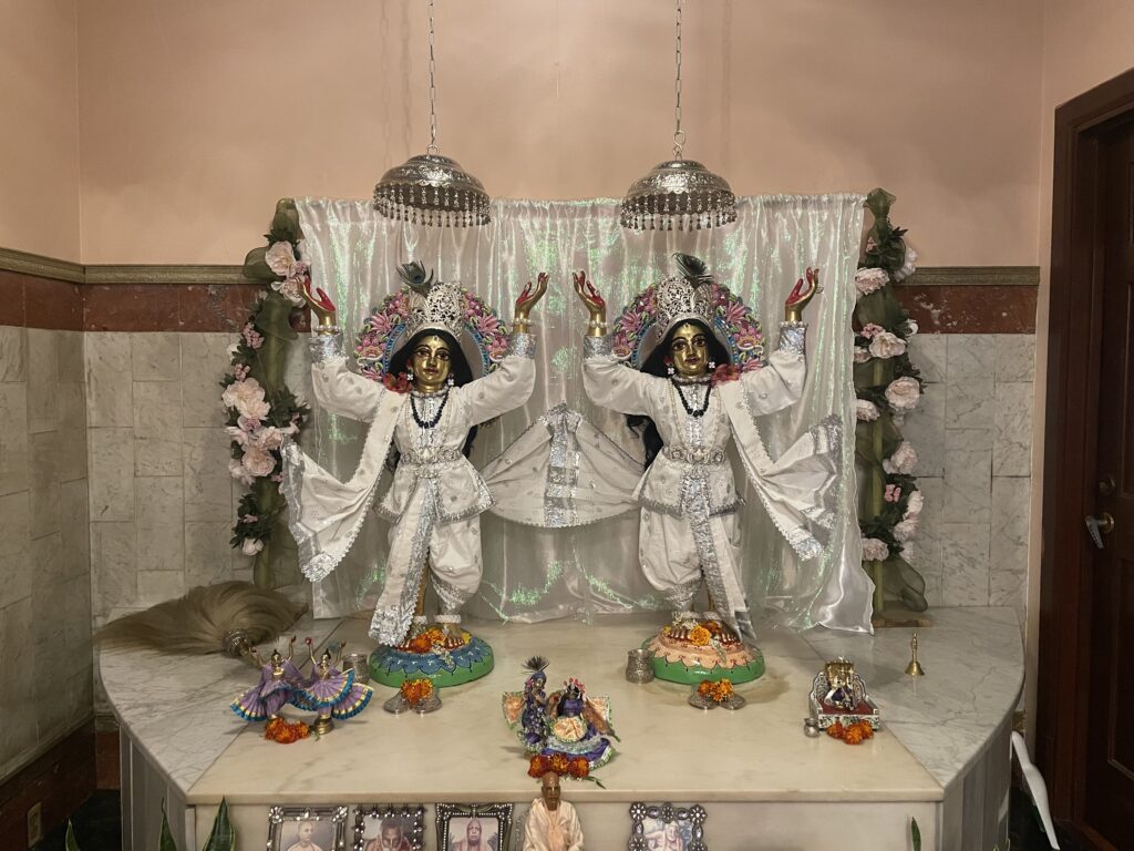 Sri Sri Nitai-Gauracandra in white and silver outfits against a white backdrop.